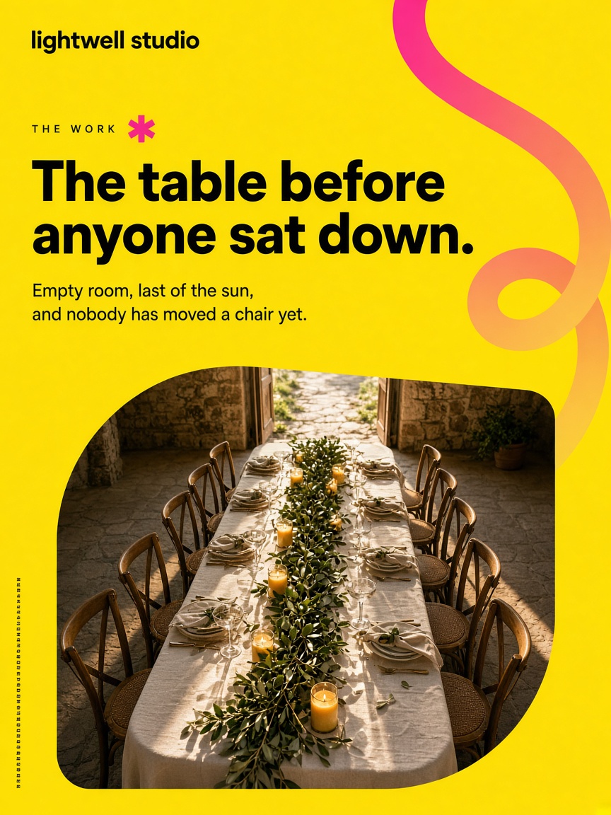 Lightwell Studio post: "The table before anyone sat down.", a long wedding table set with candles and an olive-branch runner, empty chairs down both sides, in a sunlit stone courtyard.